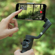 A user interacting with a smartphone attached to the DJI Osmo Mobile 6 stabilizer.